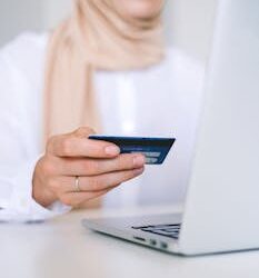A woman using a laptop and credit card for an online shopping transaction.
