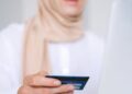 A woman using a laptop and credit card for an online shopping transaction.