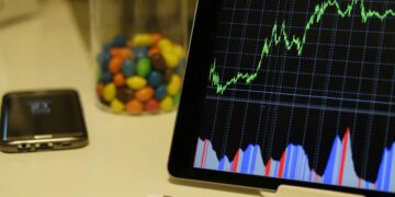 Tablet display of stock market data with smartphone and colorful candies on desk.