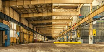 Expansive interior of an industrial warehouse showing steel beams, high ceilings, and ample space.