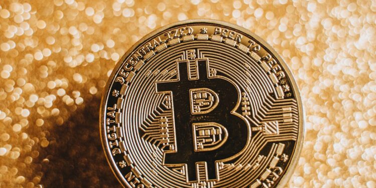 A close-up of a Bitcoin coin against a shimmering gold background, symbolizing digital currency and finance.