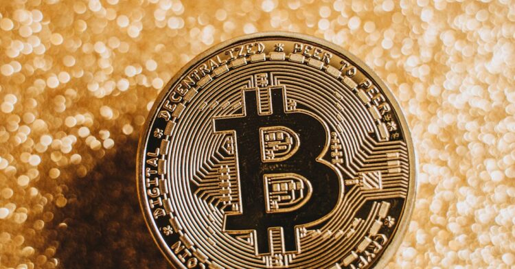 A close-up of a Bitcoin coin against a shimmering gold background, symbolizing digital currency and finance.