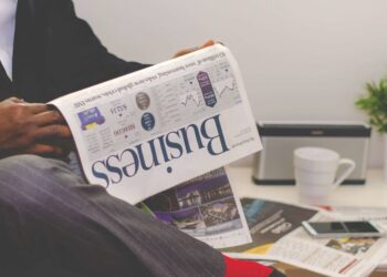 Businessman reading a financial newspaper at a desk, highlighting finance and commerce theme.