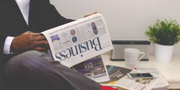 Businessman reading a financial newspaper at a desk, highlighting finance and commerce theme.